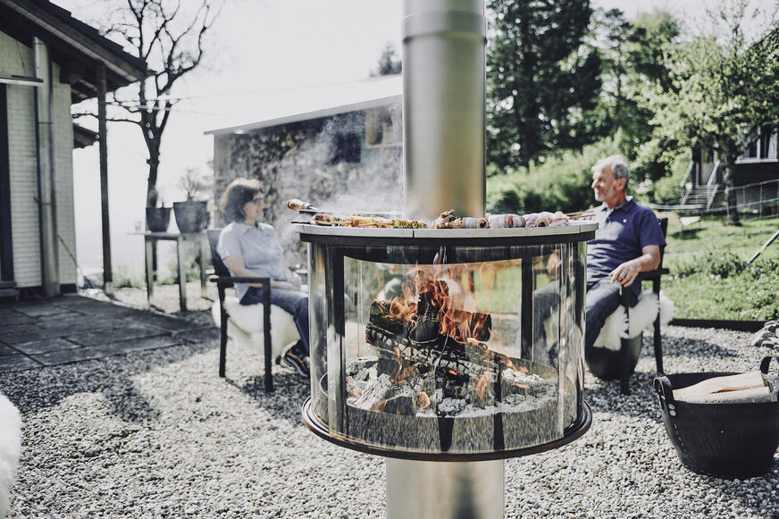 Die „Rüegg Surprise“ von Rüegg Cheminée entwickelt dank den geschlossenen Scheiben ein helles und ruhiges Feuer. Angenehme Wärme und romantisches Licht sind noch nicht alles. Auf der eleganten Outdoor-Feuerstelle lässt es sich ebenso vorzüglich kochen wie grillen.