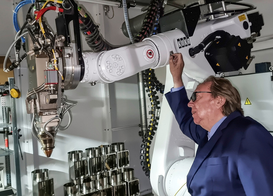 Karl-Heinz Schräder am Laserschweiß-Roboter, im Hintergrund die lasergeschweißten Formteile.