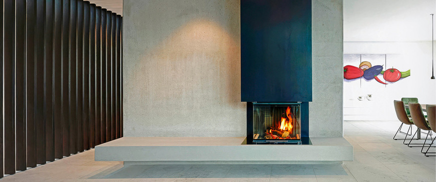 Eigentlich gehört der Kaminmantel aus Schwarzstahl ja in die Kategorie „Stahl“, aber der opulente Feuertisch aus Sichtbeton, der geschwungen in die Kaminrückwand übergeht, ist hier optisch mindestens ebenso wichtig. Von Betonofen.de, Martin Rogmans.