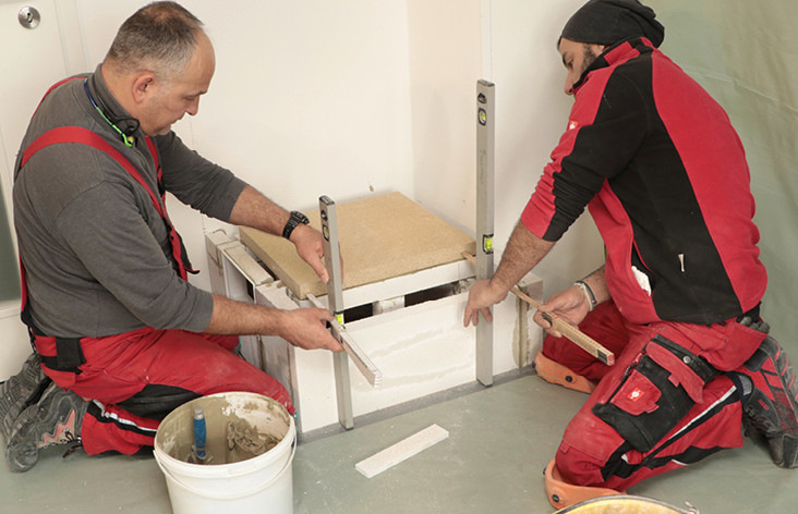  Zur Dämmung des Feuerraumbodens und damit zur Einschränkung der Wärmeabgabe nach unten an den Ofensockel wurde eine passgenaue, druckstabile vier Zentimeter starke Dämmplatte aus Vermiculite eingesetzt. Hier misst der Ofensetzer den Abstand zwischen Außen- und Feuerraumwand – dieser muss exakt passen, damit der Ofentürrahmen nach dem Verputzen der bündig an der Ofenhaut anliegt.