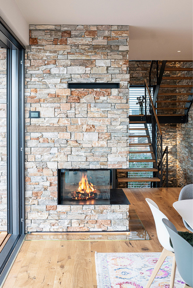 Die Materialwahl mit Holzfußboden und Steinverkleidung an den Wänden erzeugt eine außergewöhnliche Wohnatmosphäre.