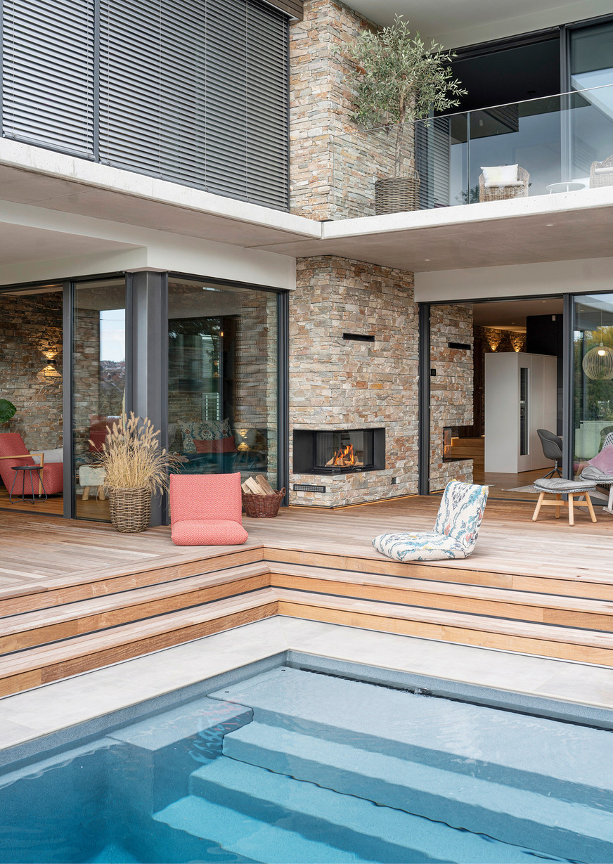 Vom Pool aus lässt sich der Baukörper mit seiner auffallenden Natursteinwand und den prägenden handwerklichen Highlights besonders gut bewundern.