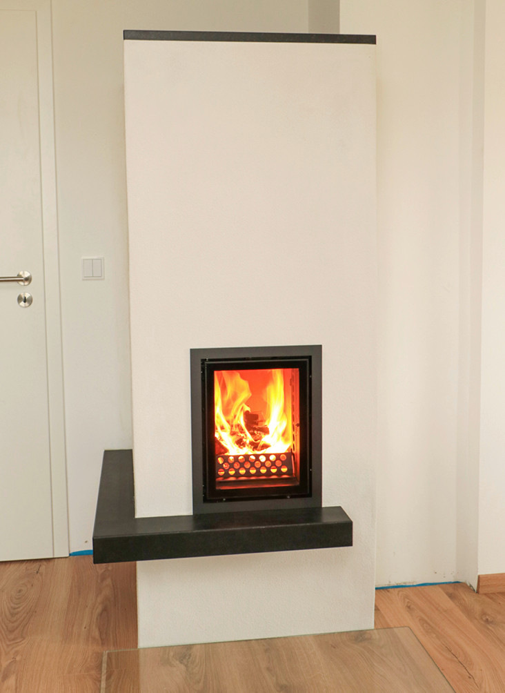 Der gewichtige Speichergrundofen macht eine gute Figur. Sein schwarzer Steinsockel ist individuelles, vom Ofensetzer handwerklich angebrachtes&nbsp;Zubehör und setzt einen schönen Akzent.