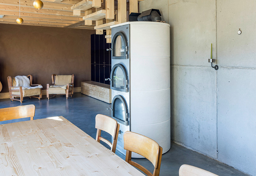 In diesem Neubau liefert der zentral aufgestellte Römerofen dank des offenen Grundrisses den Grundbedarf an Raumwärme fürs ganze Haus. Zusätzliche Strahlungswärme wird durch elektrische Vitramo-Deckenheizelemente erzeugt, von denen eines im Hintergrund erkennbar ist.