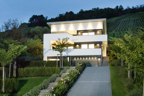 Das Sockelgeschoss dunkel, der Dachabschluss hell und das Pultdach leicht überkragend. Ein scheinbarer Fremdkörper, der dem Auge vor all dem vielen Grün überraschend willkommen ist.