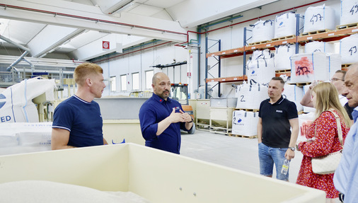 Alberto Martinez erklärt die Zusammensetzung der Majolika-Keramik. Im Vordergrund ein Basisgemisch der mineralischen Zutaten, im Hintergrund weitere Big Bags damit. - © Foto: Martin Henze
