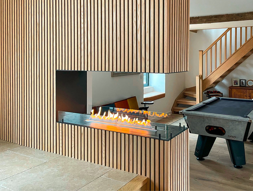 Unter der Bezeichnung I-Wood firmieren die holzbeplankten Akustikplatten, die hier die Umgebung des Ethanolkamins vom bioethanol-shop.de bilden.