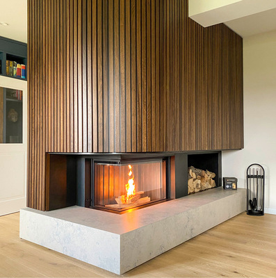 Holz als vollflächige Verkleidung eines befeuerten Holzofens? Das geht, wenn ein ausreichender Wärmeschutz gewährleistet ist? Hier ein Beispiel von Chiemsee-Öfen Kamin- und Ofenbau.