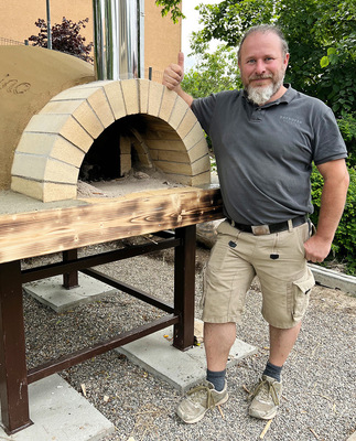 Daniel Reisinger neben einem Backofengewölbe aus Schamotte mit Lehm-Hülle.
