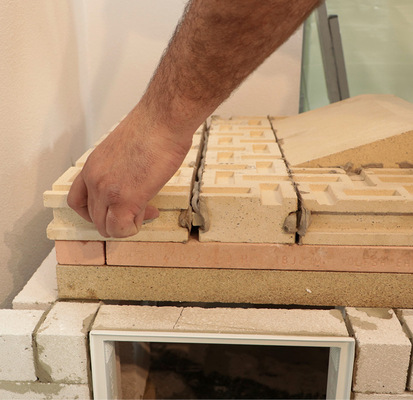 Die einzelnen Ofenschamotteplatten werden dabei mit einem speziellen Lehmmörtel verklebt und fest aneinandergefügt, wodurch eine dauerhafte, temperatur­schwankungsbeständige Verbindung entsteht.