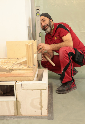 Hier misst der Ofensetzer mit der Wasserwage nach, ob die Schamottesteine im Ofentürbereich exakt senkrecht stehen. Das ist entscheidend für die spätere gerade Befestigung der Feuerraumtür.