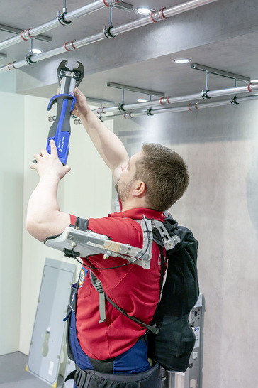 Ermüdende Arbeit über Kopf: Ein Exoskelett, das hier an den Oberarmen ansetzt, unterstützt die Muskeltätigkeiten der Arme und verlängert somit die Ausdauer des Handwerkers erheblich.