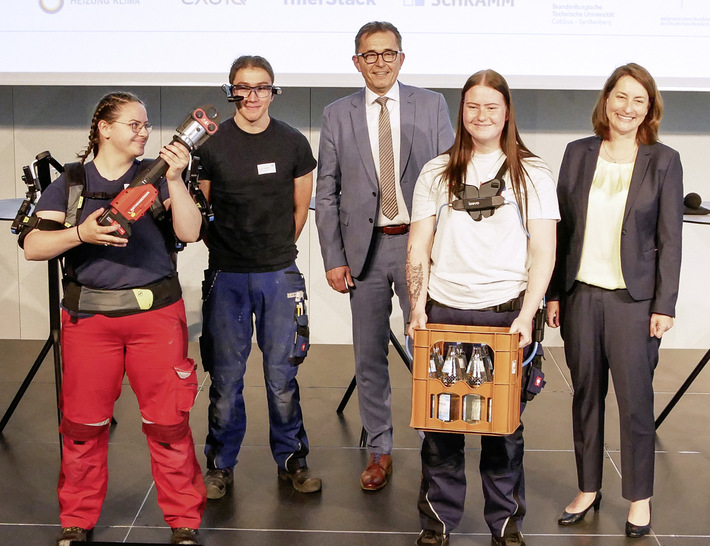 Forschungsprojekt Handwerksgeselle 4.0 abgeschlossen: Leonie Gebers (Bundesministerium für Arbeit und Soziales, rechts) und ZVSHK-Präsident Michael Hilpert (Mitte) mit Jugendlichen, die mit Exoskelett und Datenbrille praktische Erfahrungen gesammelt haben.